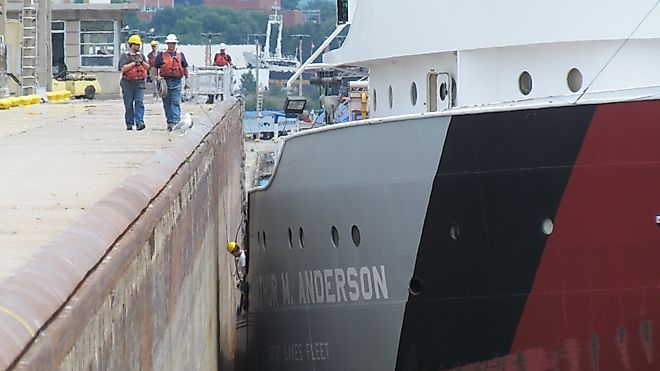 A crew member and shoreside line handlers help guide the Great Lakes freighter Arthur M. Anderson into the Poe Lock at Sault Ste. Marie, Michigan. 
