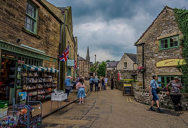 Stone shopfronts and pedestrians line a narrow street in Bakewell, Derbyshire. Editorial credit: Emad Aljumah / Shutterstock.com