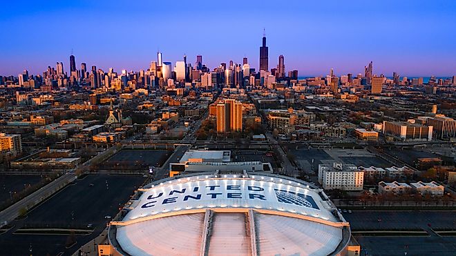 Beautiful Aerial View of Iconic United Center Stadium with Chicago Skyline in Background at Blue Hour. 