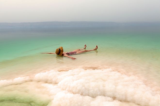 Woman relaxing in salty water of the Dead Sea. Via Shutterstock / xamnesiacx84