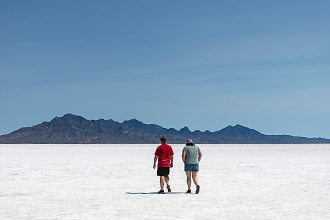 Two people walking on the white salt pan of the Bonneville Salt Flats a remnant of the Pleistocene Lake Bonneville. 