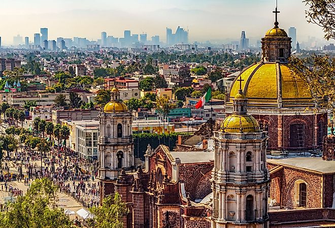 Mexico. Basilica of Our Lady of Guadalupe. Cupolas of the old basilica and cityscape of Mexico City. Image credit WitR via Shutterstock