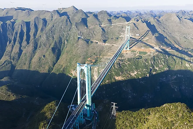 Aerial view of the Beipanjiang Bridge spanning the Huajiang Canyon in Guizhou, China. World's highest bridge structure crossing dramatic mountainous terrain with lush vegetation.
