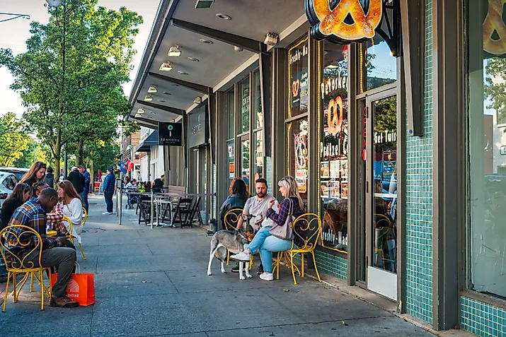 People sit on a cafe-pretzel shop patio in downtown Traverse City, Michigan, USA on a sunny day.