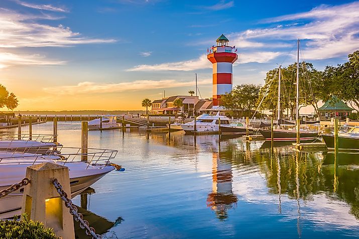The lighthouse in Hilton Head, South Carolina, stands tall at dusk with several boats dotting the nearby waters.
