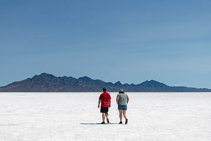 Two people walking on the white salt pan of the Bonneville Salt Flats a remnant of the Pleistocene Lake Bonneville. 