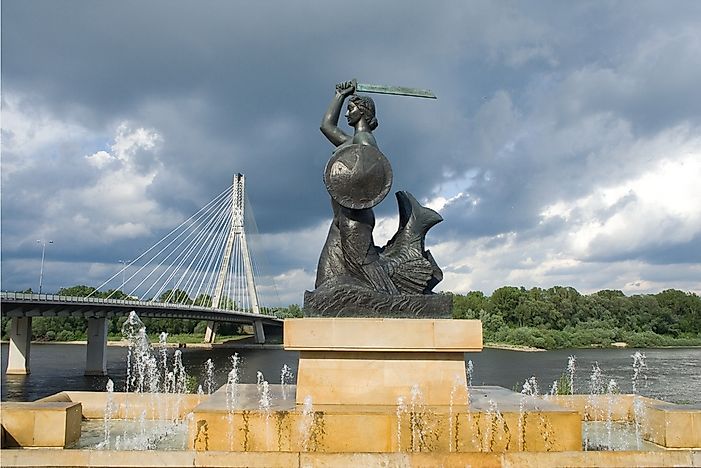 The Warsaw Mermaid in front of the Swietokrzyski Bridge crossing the Vistula River.