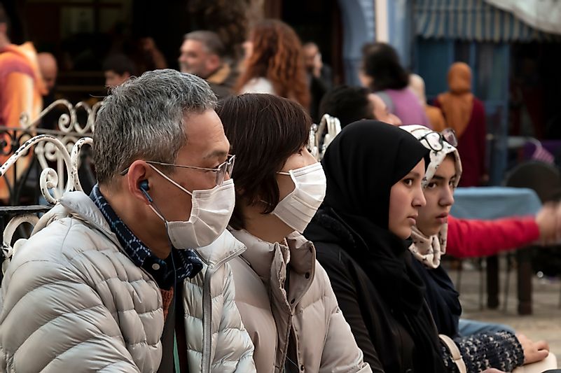 Chefchaouen, Morocco - February 25, 2017: Asian tourists with their faces covered by surgical masks. Image credit: Juan Antonio Orihuela / Shutterstock.com