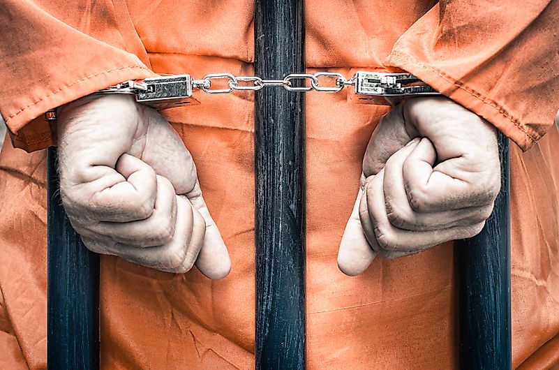Handcuffed hands of a prisoner behind the bars.