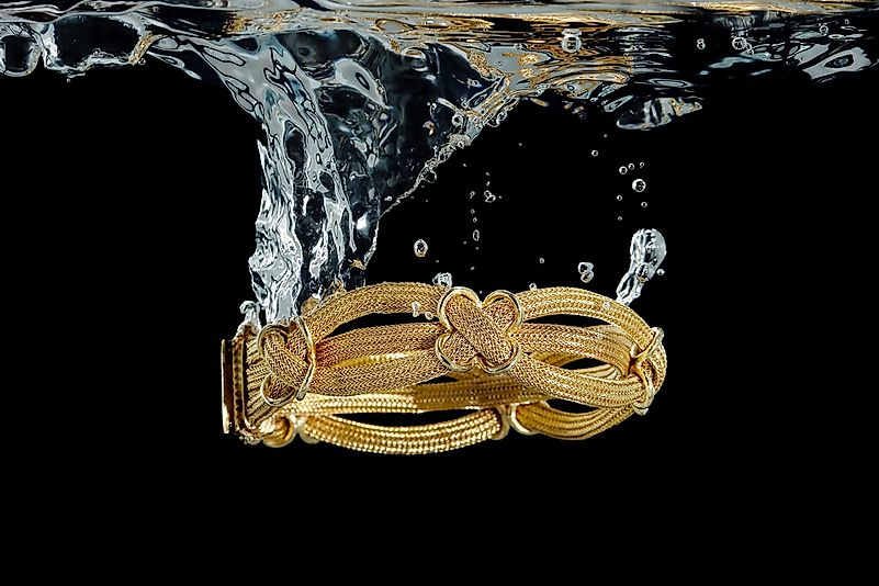 Gold bracelet submerged in water.