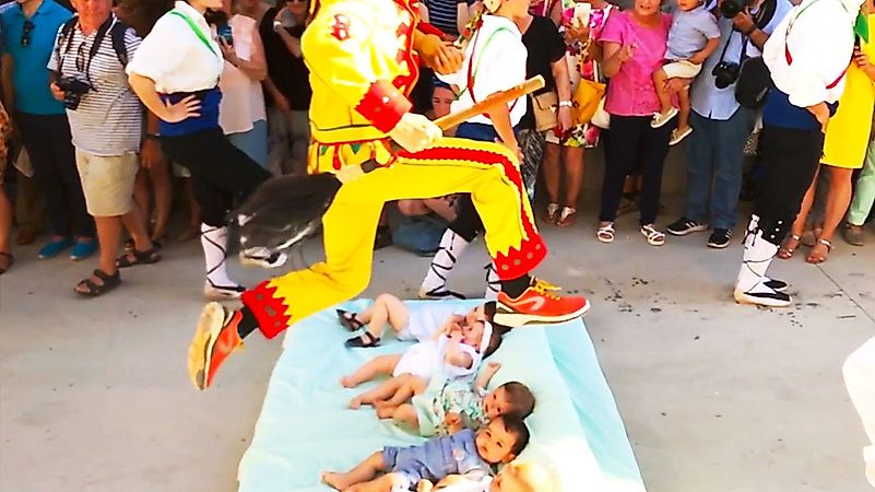 The “devils,” or men wearing costumes, then leap over the infants, in this weird version of baptism. Image credit: matadornetwork.com The “devils,” or men wearing costumes, then leap over the infants, in this weird version of baptism. Image credit: matadornetwork.com