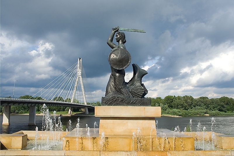 The Warsaw Mermaid in front of the Swietokrzyski Bridge crossing the Vistula River.