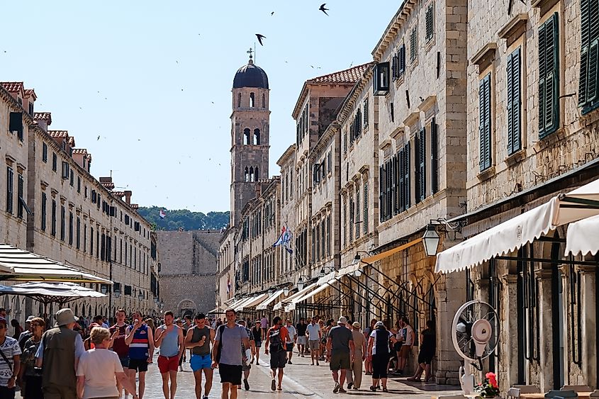 Tourists walking past historical buildings in the Old Town of Dubrovnik, Croatia.