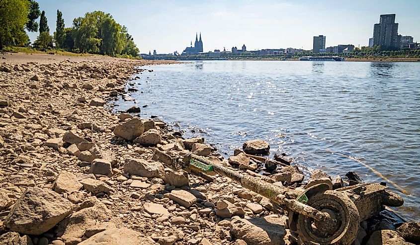 Dried up Rhine river and low water level, due to heat wave, cologne cathedral in the background, discarded e-scooter in the foreground