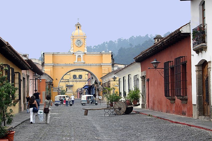 A cobblestone street leads to one of the yellow arches of Antigua, Guatemala