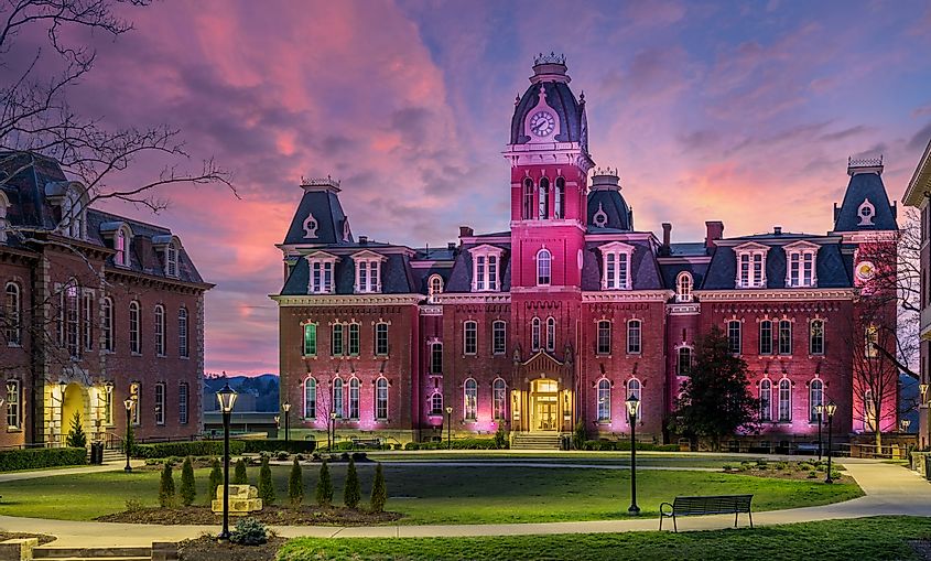 Woodburn Hall at West Virginia University (WVU) in Morgantown, WV, with a dramatic sunset behind the illuminated historic building.