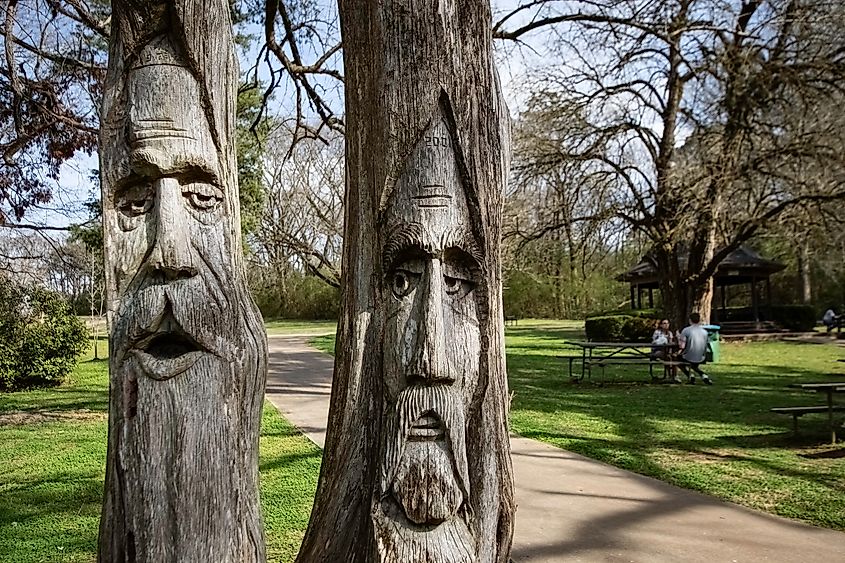 Two of the famous woodcarved faces in Orr Park by artist Tim Tingle in Montevallo, Alabama.