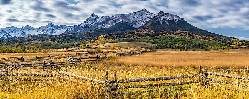 Split rail fencing lines the road leading toward Hayden Peak on Last Dollar Road near Ridgway, Colorado.