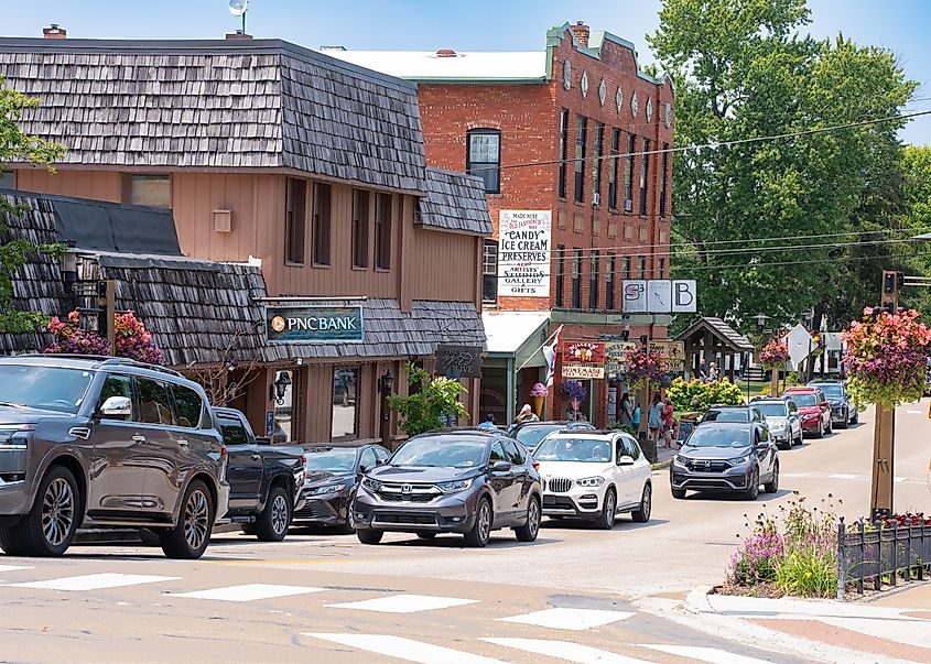 A small-town street in Nashville, Indiana, with cars, storefronts, and pedestrians lined by flower baskets.