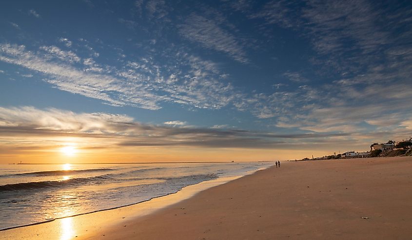 A beautiful sunset on the beach of Mazagon, Spain. Silhouetted by walkers on the shore.