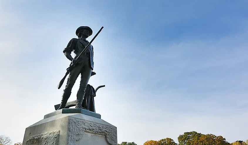 The Minute Man statue and North Bridge at Minute Man National Historic Park with fall foliage as background, Concord Massachusetts.