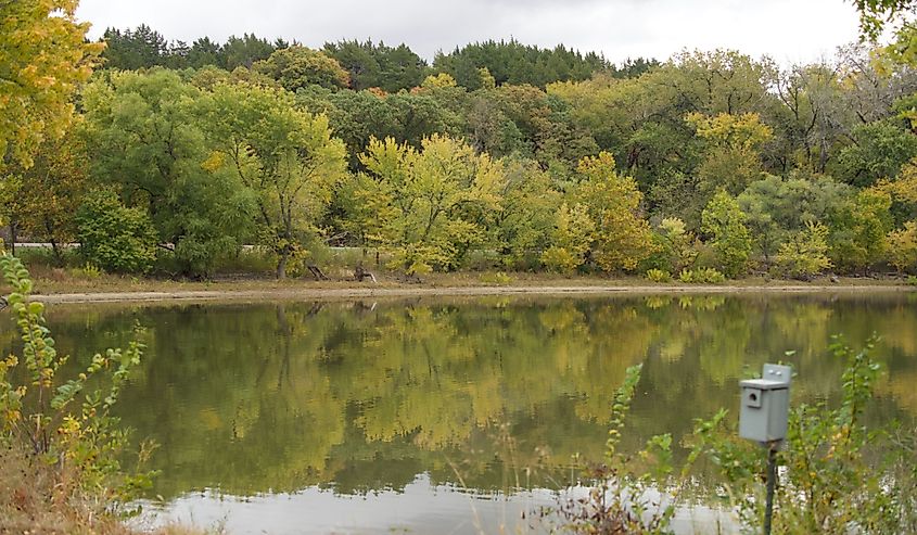 A landscape of Tuttle Creek Lake surrounded by greenery under a cloudy sky in Kansas, the US