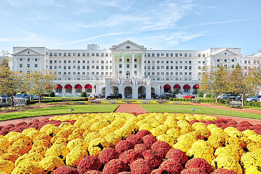 Greenbrier Hotel resort exterior entrance with landscaped flowers, lawn, parked cars, in West Virginia.