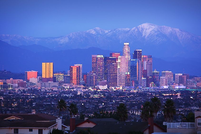 Downtown Los Angeles skyline over snowy mountains at twilight