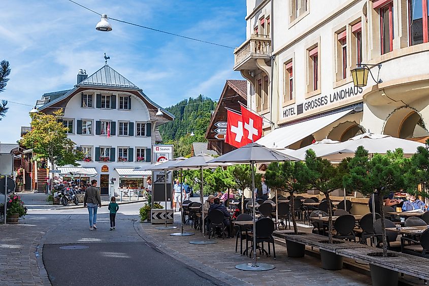 Saanen, Switzerland - September 6 2025: People enjoying coffee on a sunny terrace in the village center, with the charming hotel and alpine atmosphere around.
