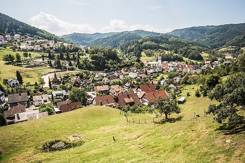 A wide view of Ottenhöfen im Schwarzwald, where red-roofed houses sit among rolling hills and forested slopes in Germany’s Black Forest.