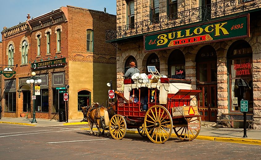 DEADWOOD, SD, USA - SEPTEMBER 15, 2020: An old-fashioned stagecoach carries tourists past the old Bullock Hotel on Main St. in this Black Hills gold rush town, famous for outlaws and entrepreneurs.