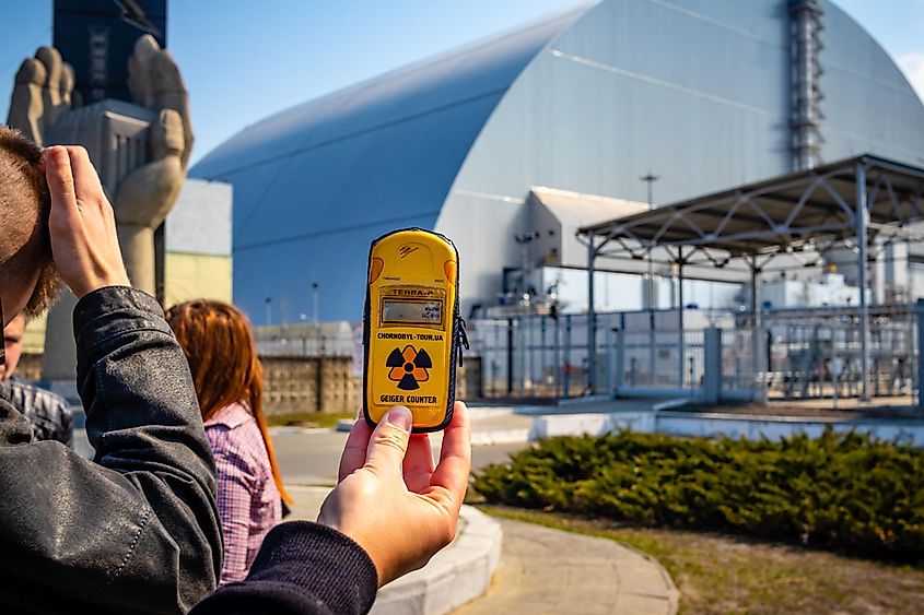 Tourists with a Geiger Counter stand in front of the New Safe Confinement arch over disaster reactor number 4 in Chernobyl, Ukraine.