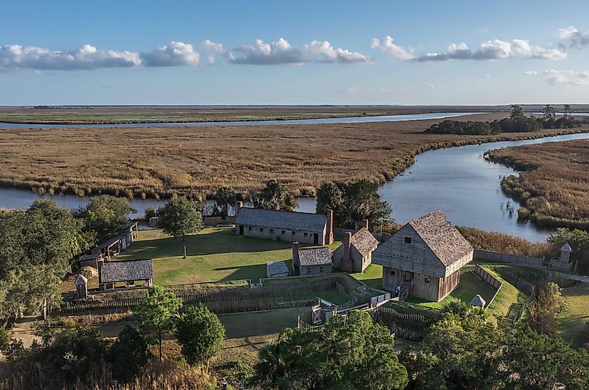 Aerial view of Fort King George, the oldest English fort on the Georgia coast, featuring a wooden palisade and gun ports for cannons, with a blue cloudy sky backdrop near Darien, Georgia, USA.