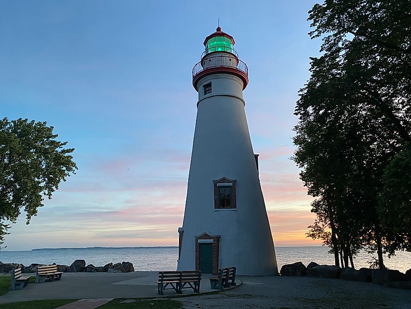 A lighthouse flashes its green beacon at dawn. 