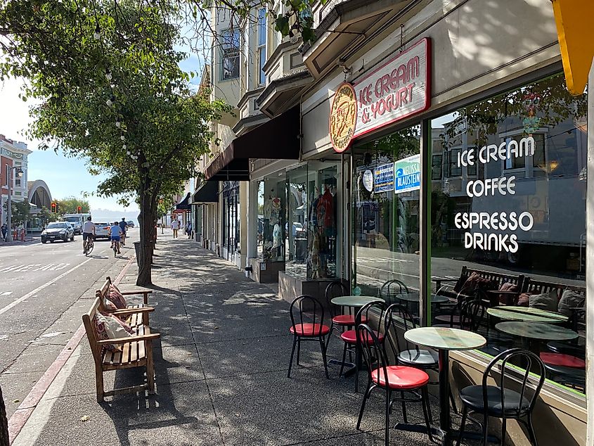 A group of cyclists passes an ice cream parlour and other cute shops in downtown Sausalito.