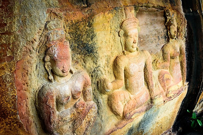 Faces on ancient stone of mountain in Cambodia, showing weathering and environmental damage due to acid rain.