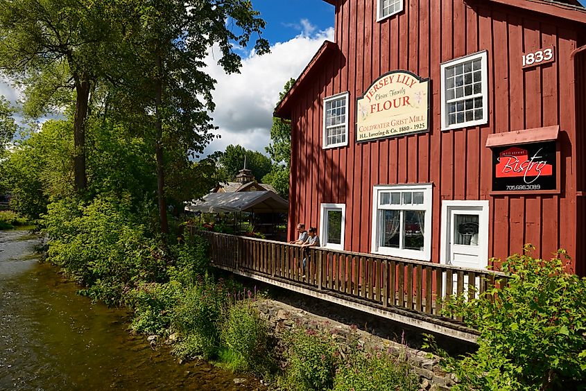 Editorial Photo Credit: Reimar via Shutterstock. Coldwater, Ontario, Canada - August 10, 2013: Summer visitors at the restored Coldwater Grist Mill with the flowing river