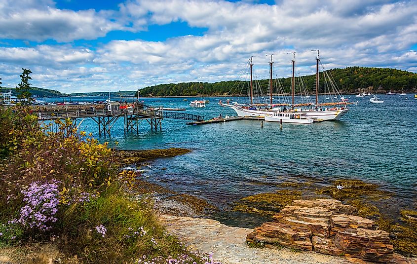 Rocky coast and view of boats in a harbor at Frenchman Bay in Bar Harbor, Maine
