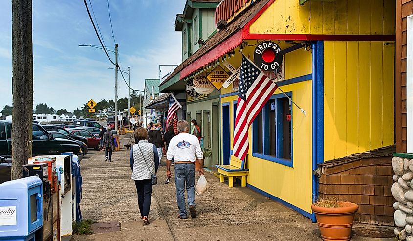 People walking on a sidewalk in front of shops in downtown Depoe Bay Oregon