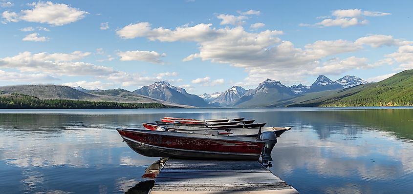 Stock Photo ID: 1750582436  Rustic motor boats lined up in a perfect row on a wooden dock looking out onto Lake McDonald in the beautiful Glacier National Park, Montana
