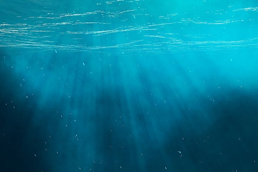 Shafts of sunlight fading into deep blue water.