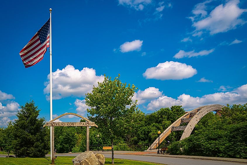 Houlton Riverfront Park in Aroostook County, Northern Maine on a summer day with the American Flag waving in the wind and the view of arching Gateway Crossing Bridge