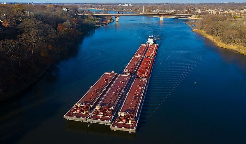 A red barge ships cargo down the Illinois River near Ottawa, Illinois. Aerial photograph via drone.