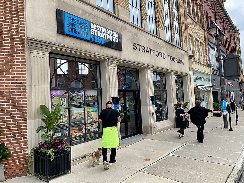 People strolling on the sidewalk outside of Stratford, Ontario's tourist center.