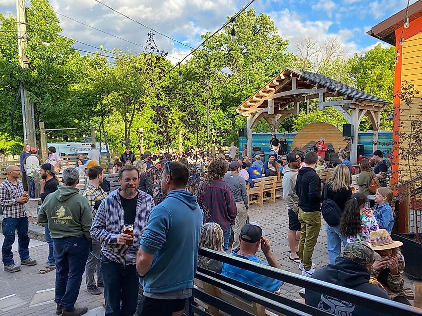 An amiable crowd gathers out back of a brewery to enjoy live music.