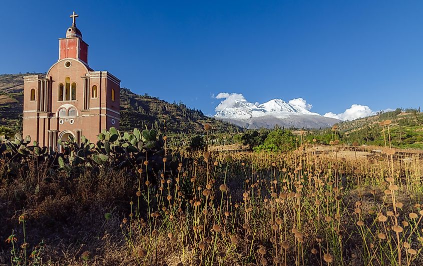 Remains of the facade of the church of the old yungay destroyed by a flood with the huascaran mountain in the background and vegetation in the foreground, peru