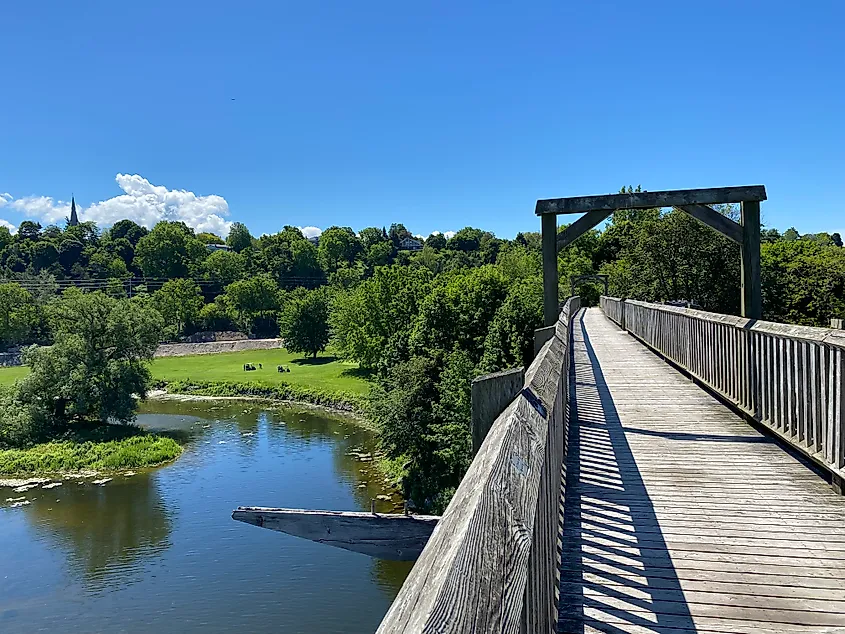 A wooden rail bridge (now pedestrian) crosses high above a river valley. 