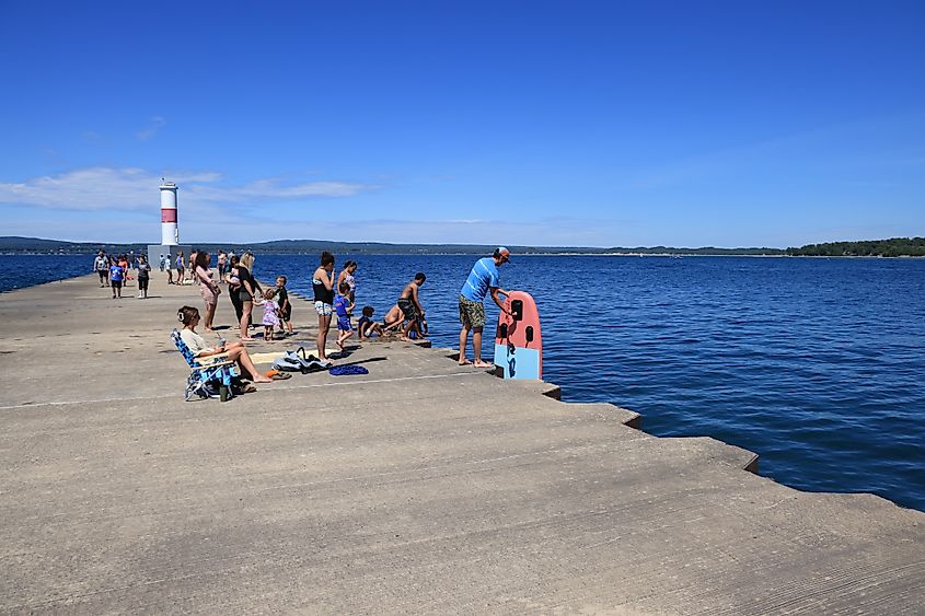 People enjoying a walk or relaxing on the pierhead and lighthouse breakwater into Little Traverse Bay at Petoskey in Northern Michigan