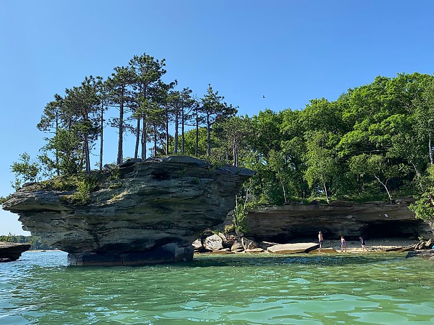 A group of docked kayakers investigating a striated floating island and sea cave.