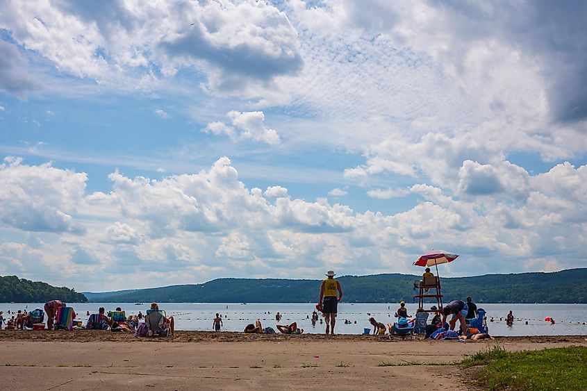 Crowds flock to the beach at Glimmer-glass State Park, a popular summer destination for camping and swimming, at Otsego Lake to escape the heat, via JWCohen / Shutterstock.com